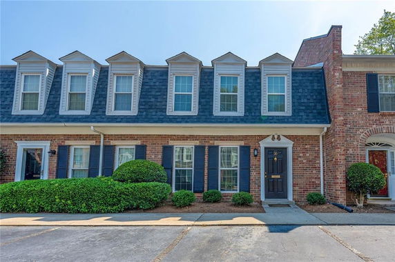 Front view of a two-story townhouse with brick facade and dormer windows.