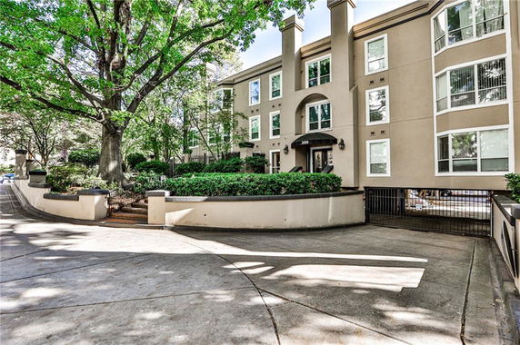 Front view of a three-story residential building with large windows and gated entrance.