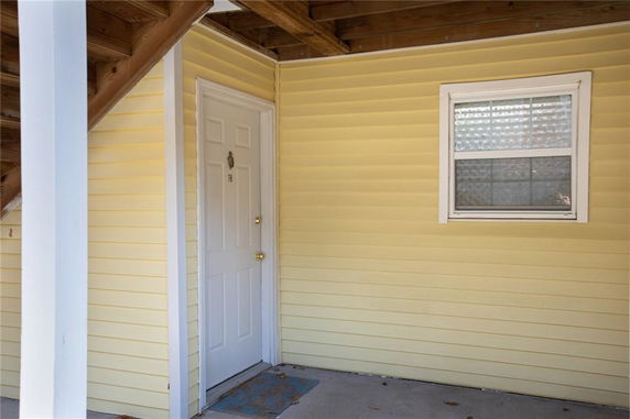 Entrance view of a building with yellow siding and a white door.