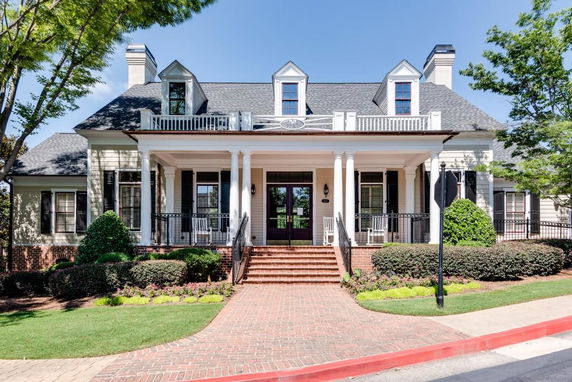 Front view of a multi-story house with a porch and multiple chimneys.