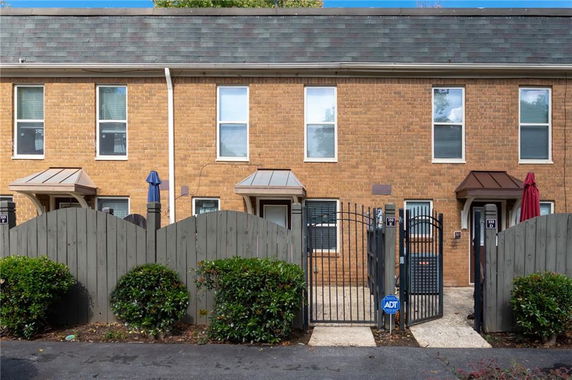 Front view of a two-story brick townhouse with gated entrance.