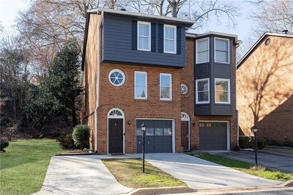 Front view of a three-story brick house with a garage and multiple windows.