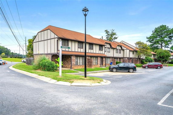 Front view of a multi-story residential building with a brown roof and parking area.
