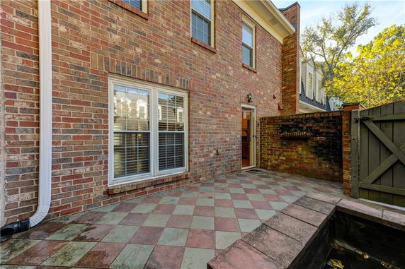 Rear view of a two-story brick house with a small patio.