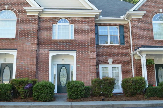 Front view of a two-story brick townhouse with arched windows and white trim.