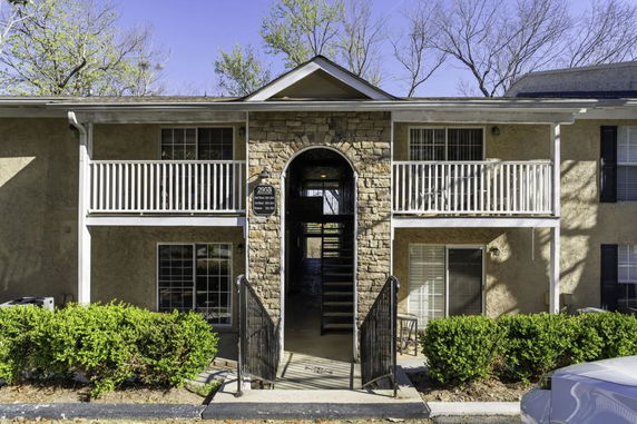 Front view of a two-story residential building with a central stone archway and balconies.