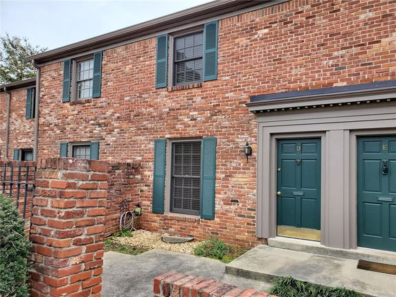 Front view of a two-story brick building with green shutters and doors.
