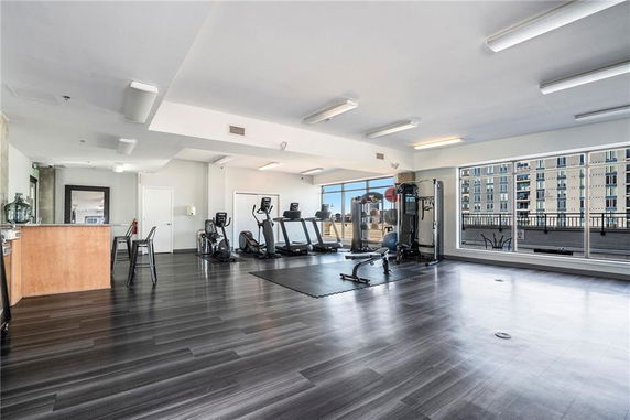 Interior view of a gym area with exercise equipment and large windows.