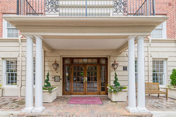 Front view of a building entrance with columns and wooden doors.