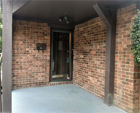 Front view of a brick-walled porch area with a glass door.