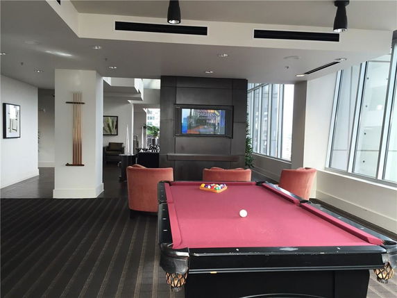 Indoor area with a billiards table, chairs, and a television on the wall.