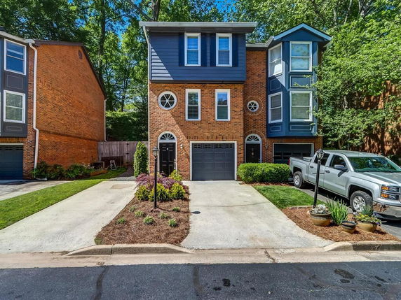 Front view of a multi-story brick house with garage and bay windows.