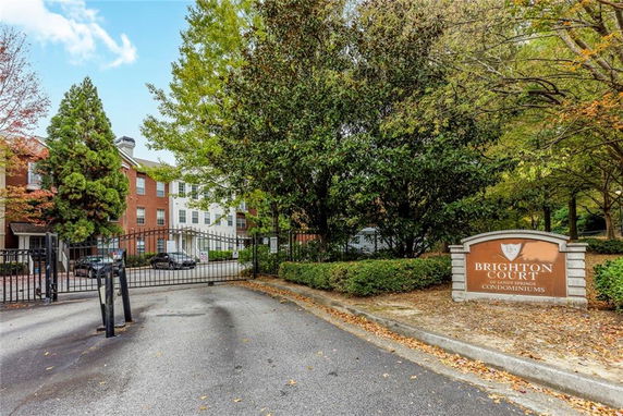 Front view of a condominium complex with multiple stories, featuring a gated entrance and a sign for Brighton Court.