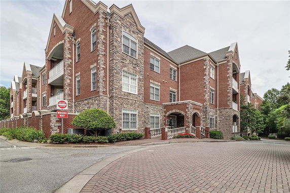 Front view of a multi-story brick building with balconies and arched entryways.
