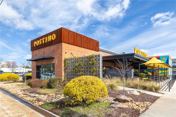 Front view of a commercial building with brick and colorful accents, featuring a sign with the name 'Postino'.