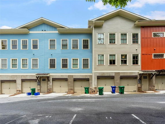 Front view of a multi-story townhouse with garages on the ground level.