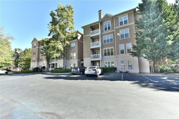 Front view of a multi-story apartment building with balconies and parking area.