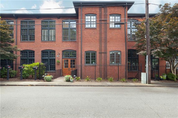 Front view of a multi-story brick building with large windows and a gated entrance.