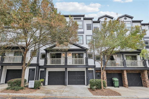 Front view of a multi-story townhouse with balconies and garages.