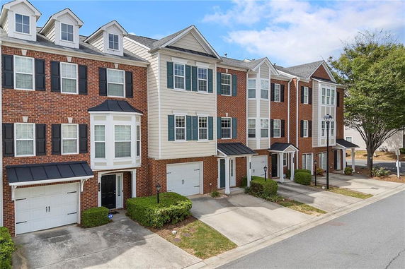 Front view of a multi-story townhouse complex with brick and siding exterior.