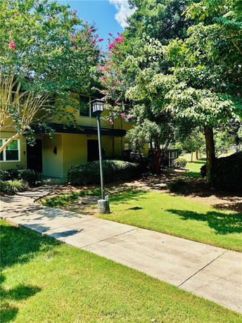 Front view of a two-story house with a walkway and surrounding trees.