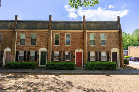 Front view of a row of two-story townhouses with brick exterior and various colored doors.