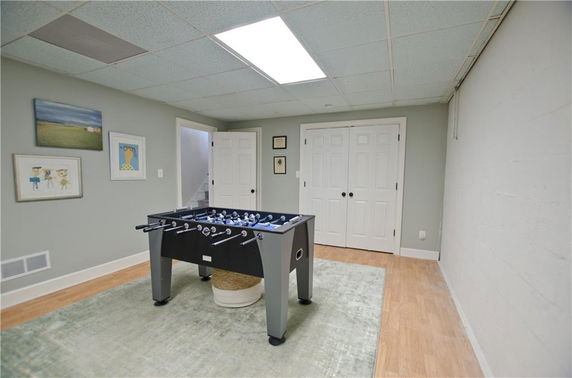 Room with a foosball table and framed artwork on the walls.