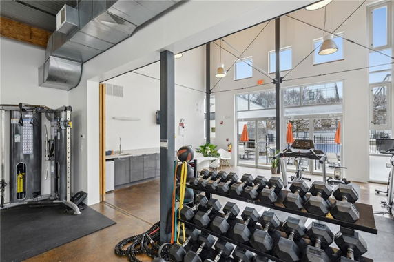Interior view of a gym area with exercise equipment and large windows.