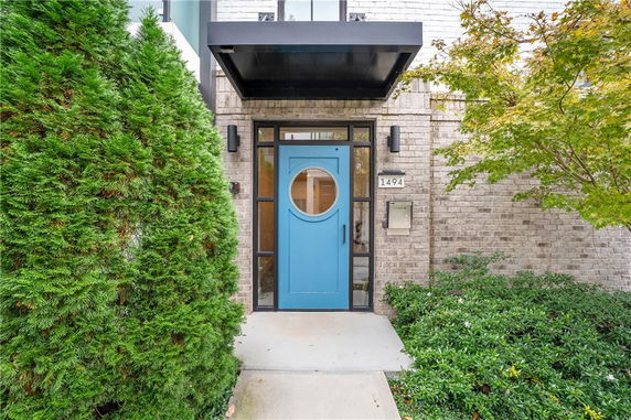 Front view of a house entrance with a distinctive blue door featuring a circular window.