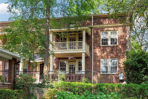 Front view of a two-story brick house with a balcony and multiple windows.