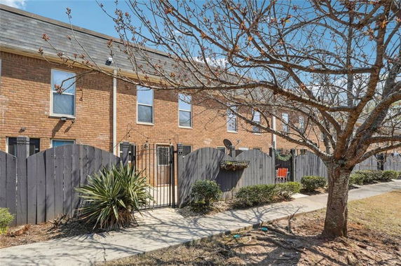 Front view of a two-story brick townhouse with black wooden fencing.