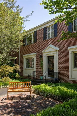 Front view of a two-story brick house with dark shutters and a small porch entrance.