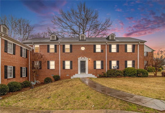 Front view of a two-story brick house with a central entrance and dormer windows.