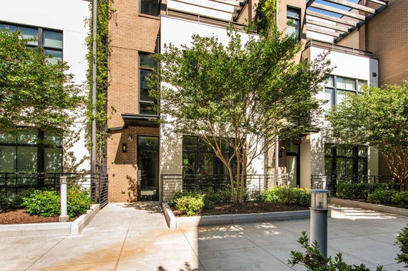 Front view of a modern multi-story building with trees and landscaping.