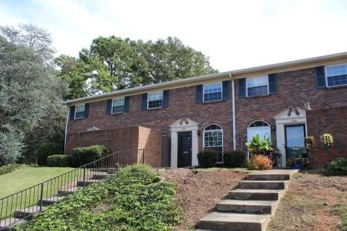 Front view of a two-story brick townhouse with stairs leading to the entrance.