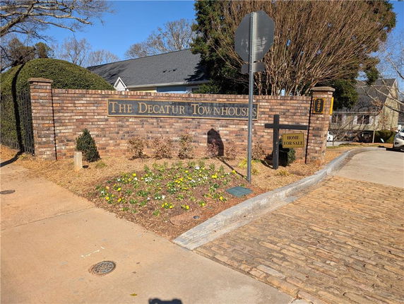 Entrance view of a townhouse community with a brick sign that reads 'The Decatur Town Houses'.