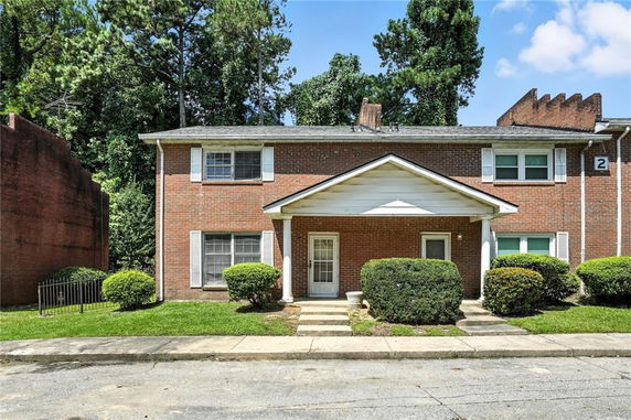 Front view of a two-story brick house with a gable roof and two entry doors.