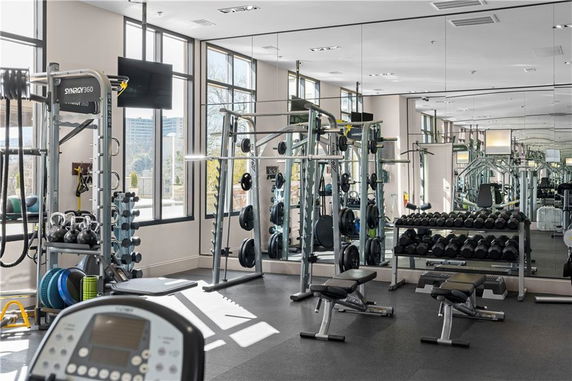 Interior view of a gym area with weightlifting equipment and mirrors.
