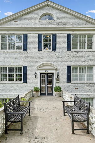Front view of a two-story brick house with blue shutters and arched doorway.