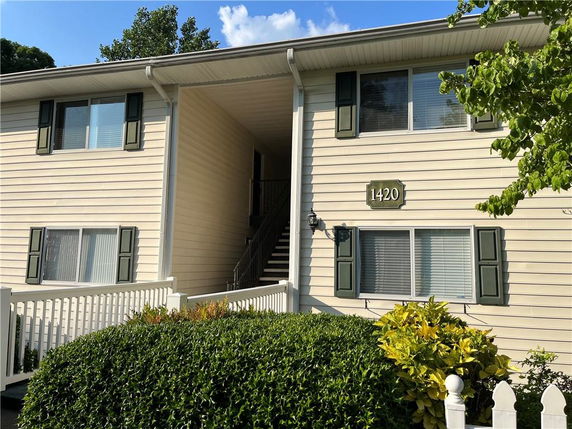 Front view of a two-story building with a central staircase and green shutters.