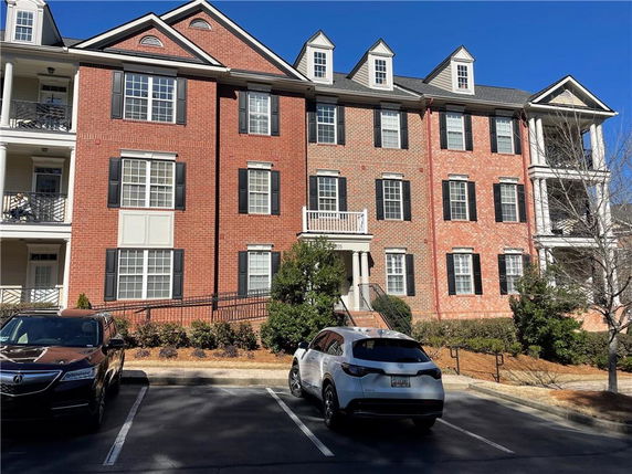 Front view of a multi-story brick residential building with dormer windows and balconies.