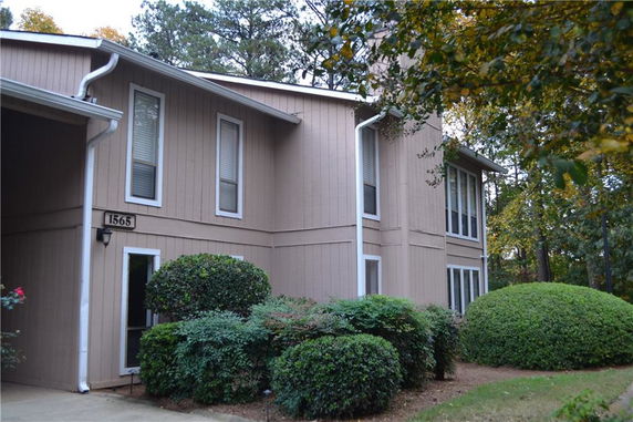 Front view of a two-story house with vertical wooden siding and several tall windows.