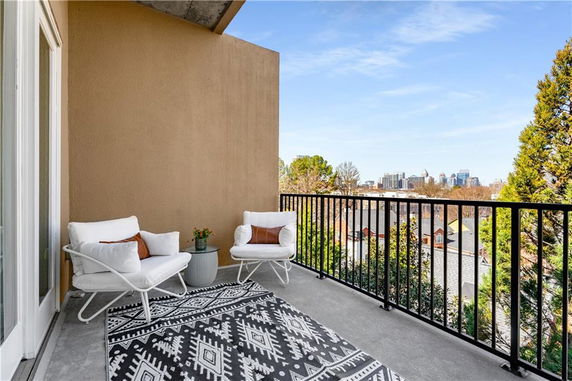 Balcony with chairs overlooking a cityscape and treetops.