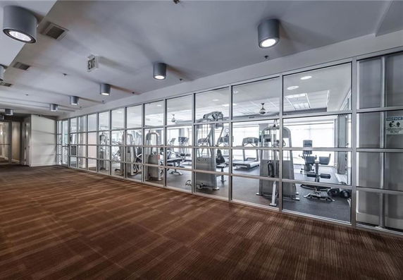 Interior view of a gym with exercise equipment behind glass walls.