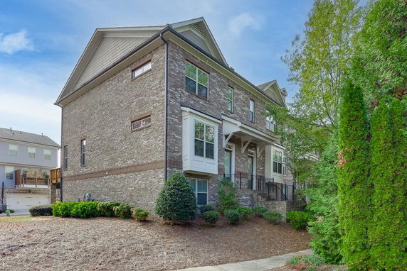 Side view of a multi-story brick house with a pitched roof.