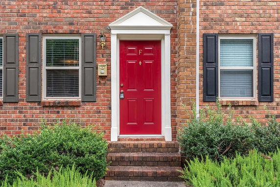 Front view of a house with a red door and brick exterior.