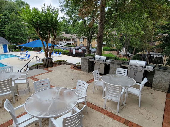 Outdoor area with a swimming pool, lounge chairs, and barbecue grills.