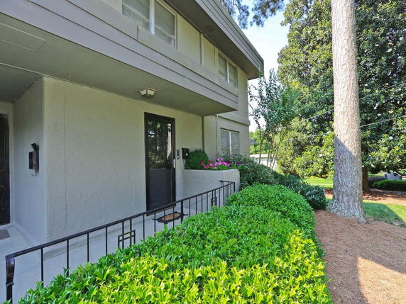 Front view of a two-story building with shrubs and trees.