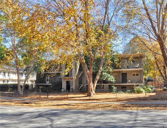 Front view of a multi-story residential building surrounded by trees.