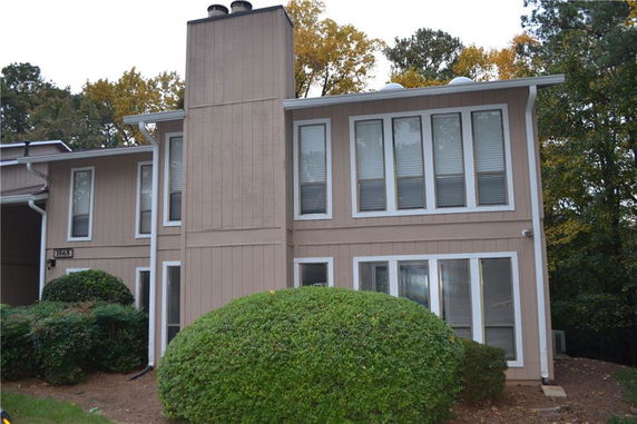 Front view of a two-story house with multiple large windows and a chimney.
